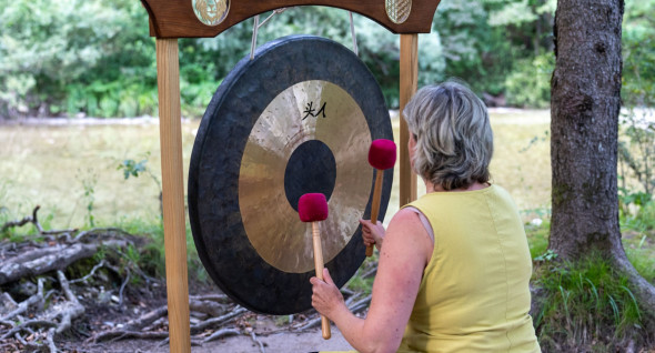 A woman doing the sound bath with a gong near Idrija