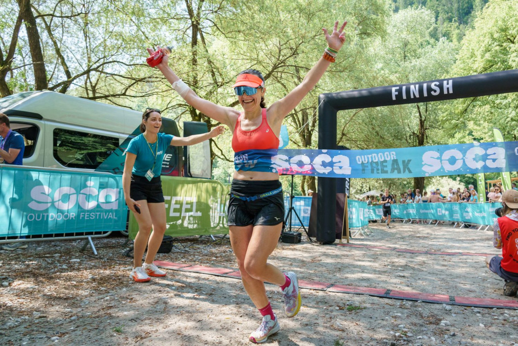 A female runner crossing the finish line at the I feel Slovenia Soča Outdoor Festival